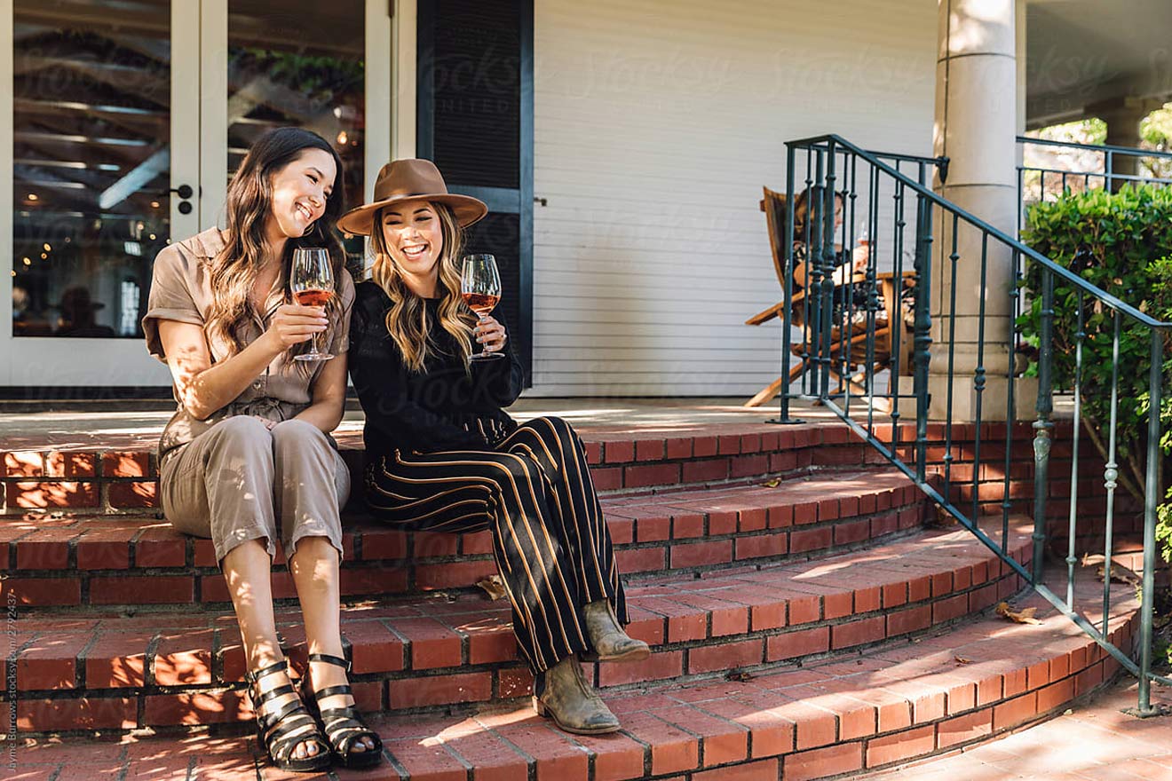 two women sitting on a step enjoying a glass of wine