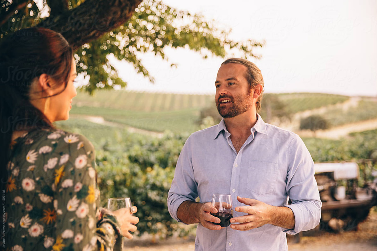 man and women talking with vineyard in backdrop