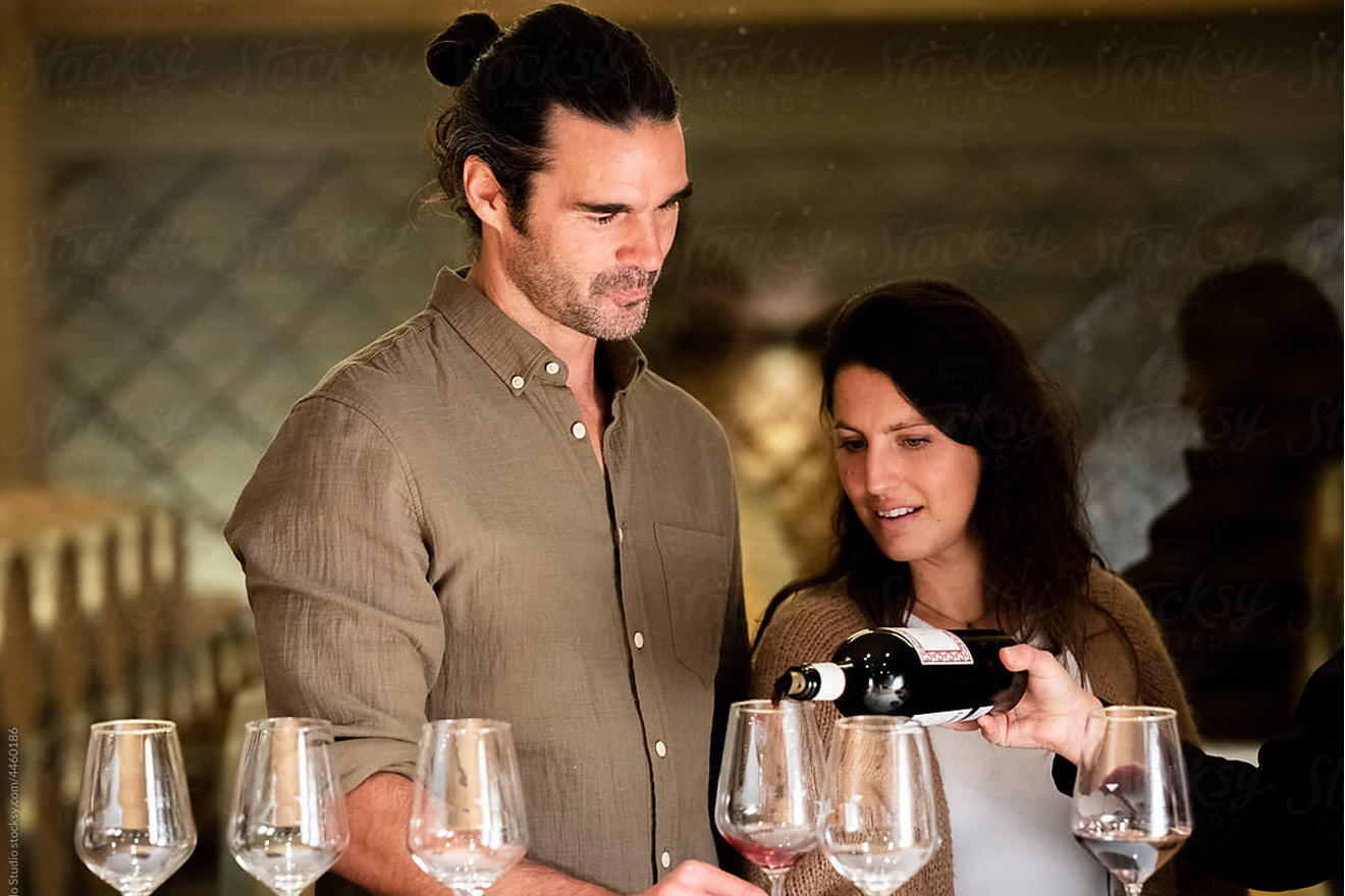 man holding wine glass while someone pours wine