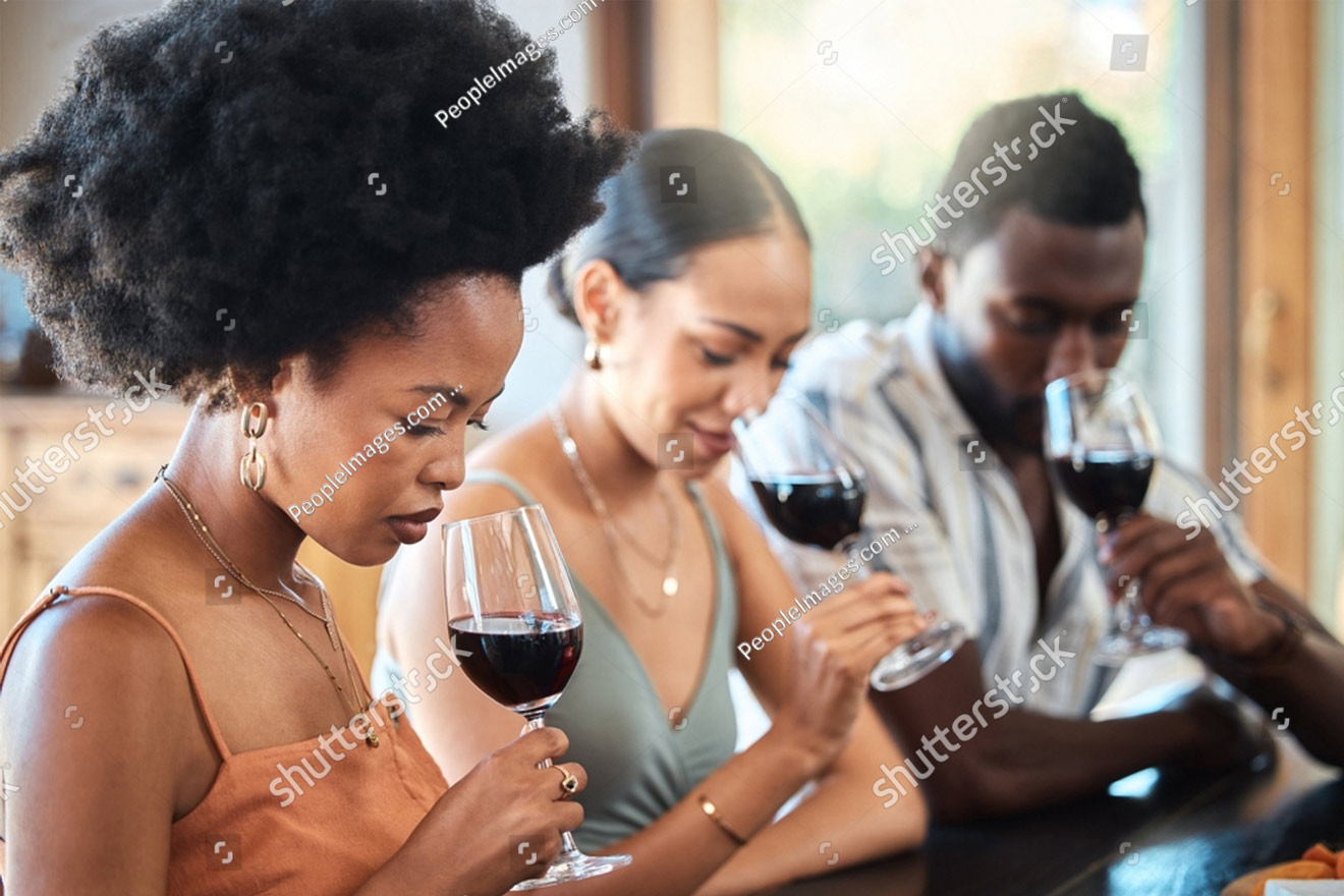 two women and a man enjoying the smell of wine while winetasting
